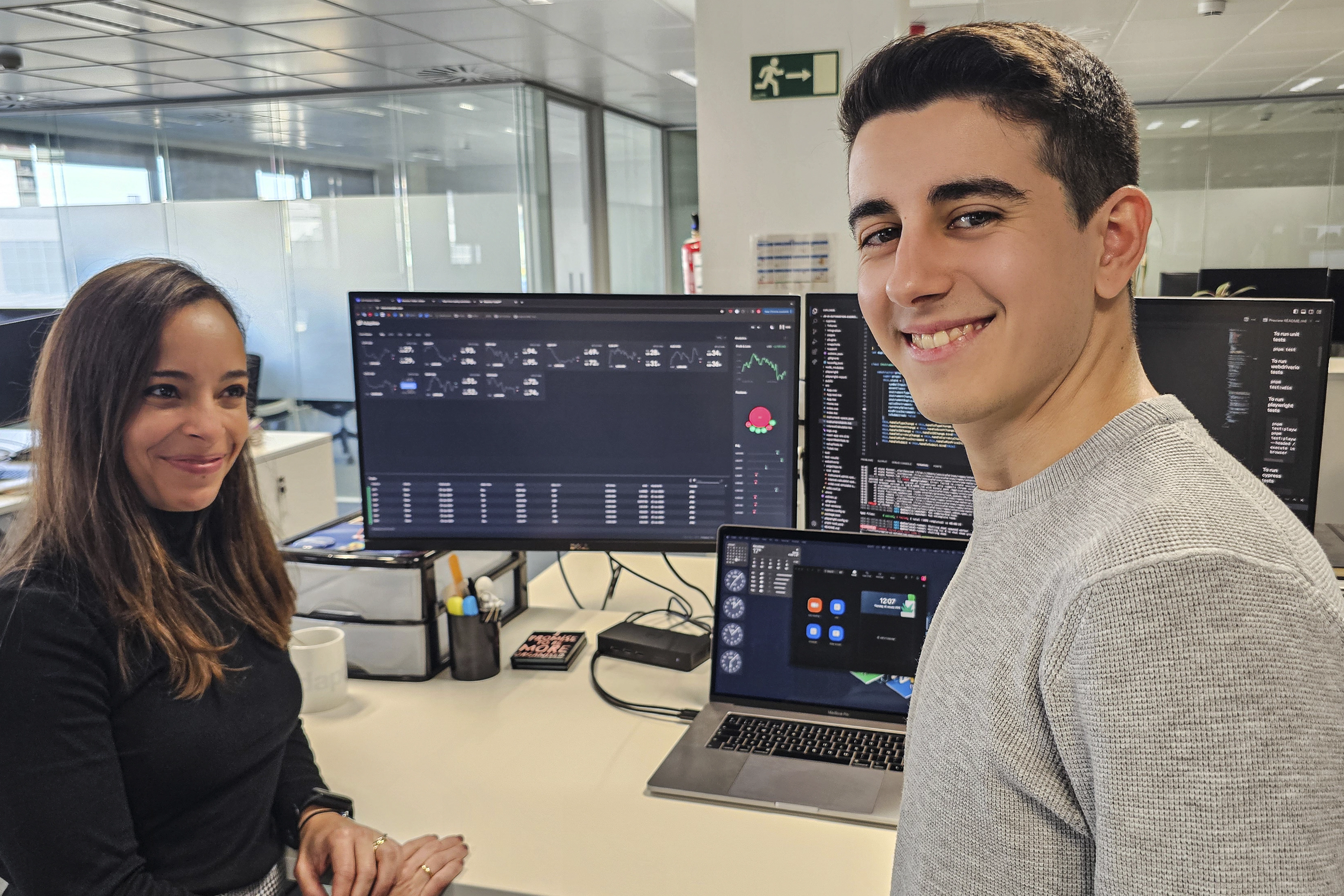 Two employees collaborating in front of a screen at Adaptive, working together on a project