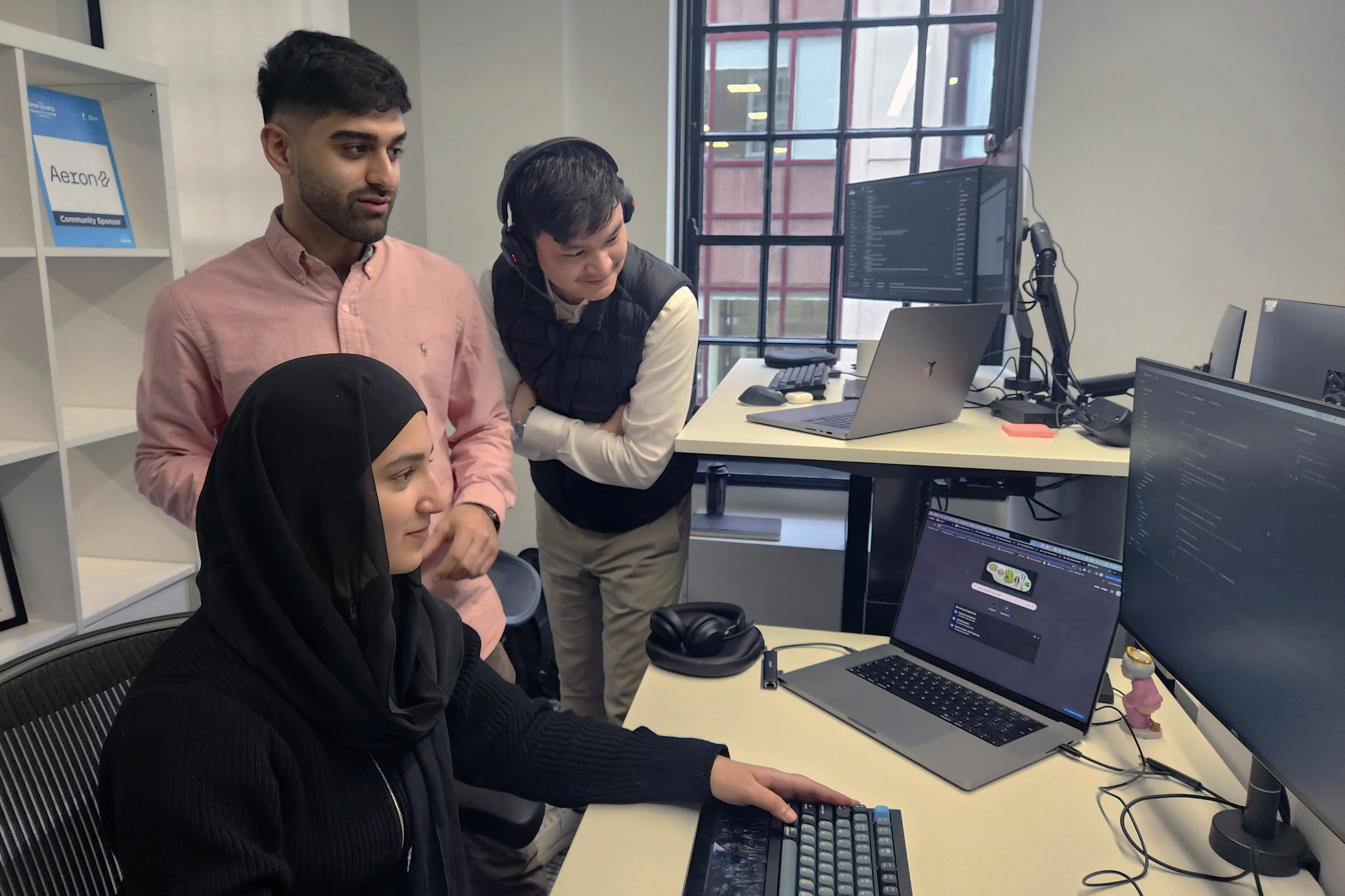 Three ECP trainees collaborating in front of a screen at Adaptive, working together on a project